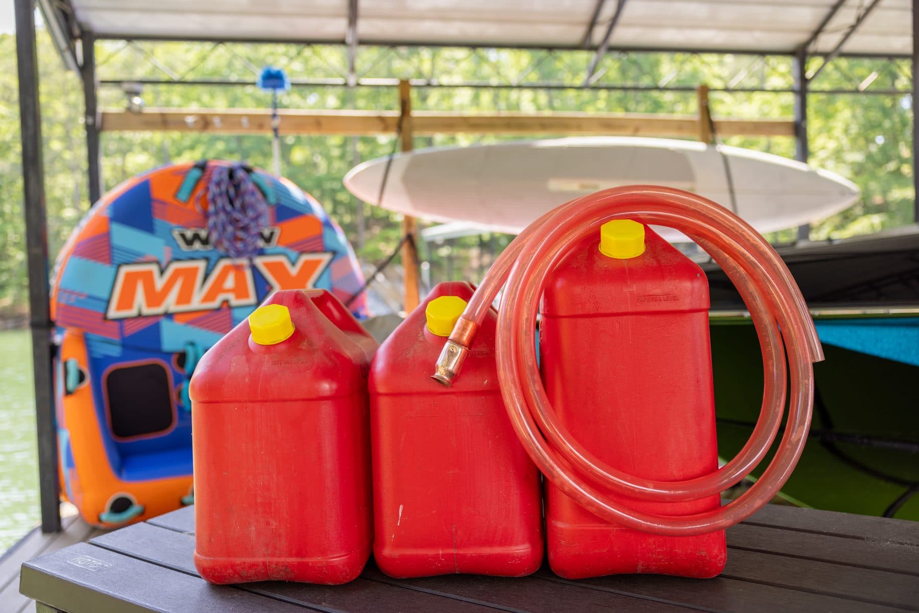 Gas cans and a coiled FlowPro siphon on a boat at the dock